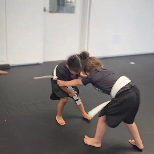 Two girls practising wrestling on the mats