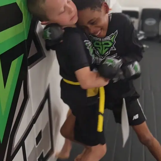 Two kids grappling in class, both smiling